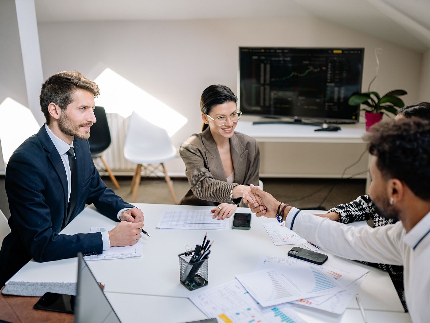 Colleagues shake hands across the table at a business meeting